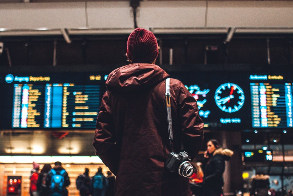 Jeune homme dans un aéroport regardant le tableau des vols