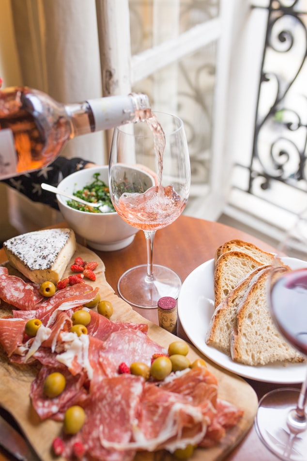 photographie d'une assiette de charcuterie et d'un verre se remplissant de vin