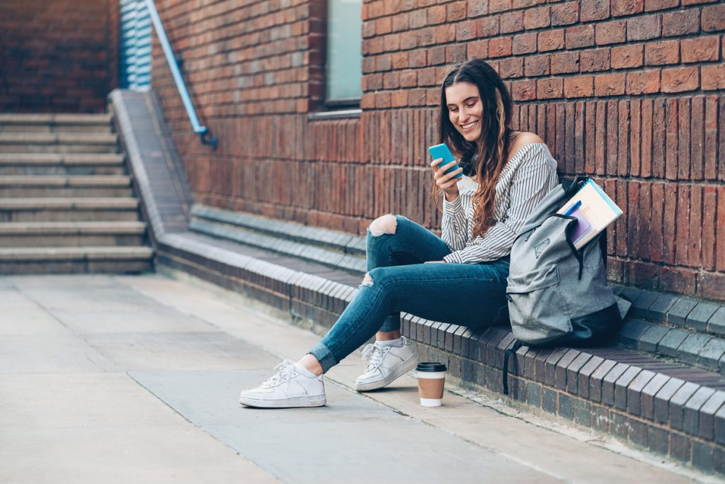 jeune étudiante riant en regardant un portable