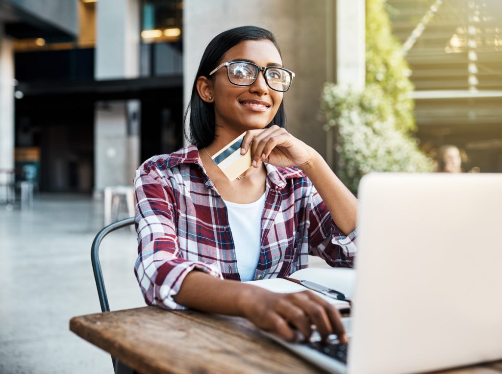 Cropped shot of a young female student using a laptop and credit card outside on campus