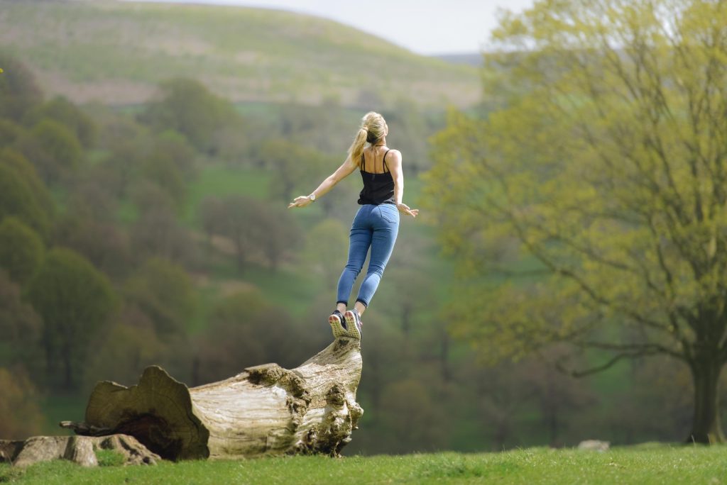 jeune femme debout sur le un tronc d'arbre