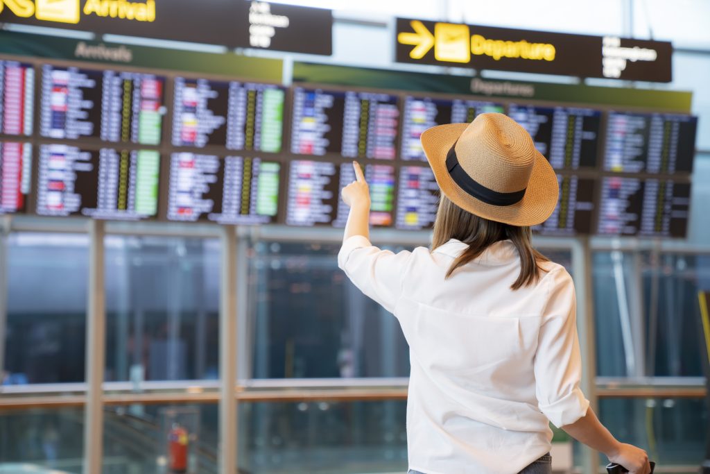 jeune femme devant un tableau d'horaire dans un aéroport