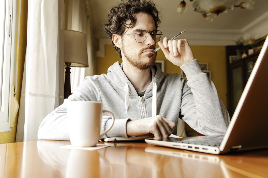 homme tapant sur un ordinateur avec un café à sa droite