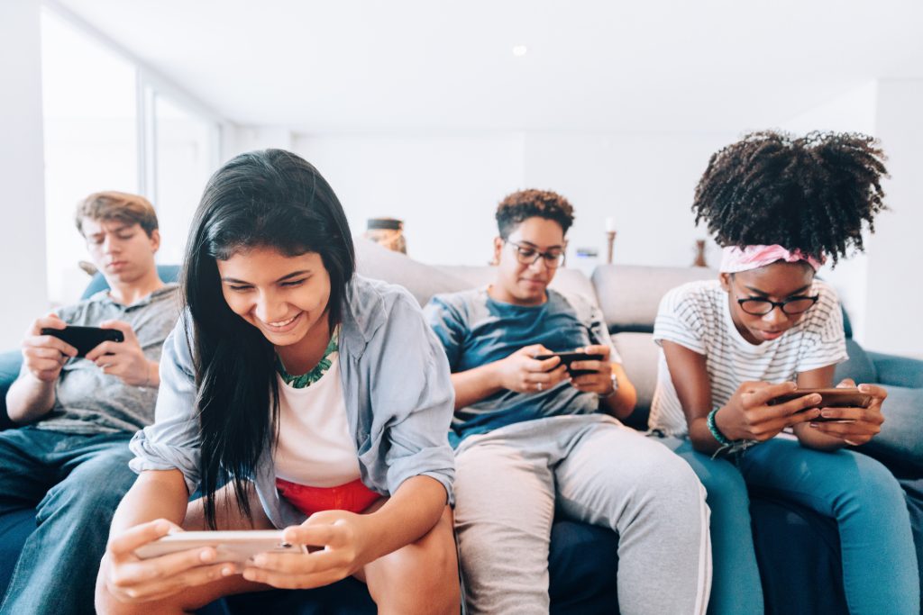 groupe de jeunes assis sur un canapé en regardant leurs mobiles