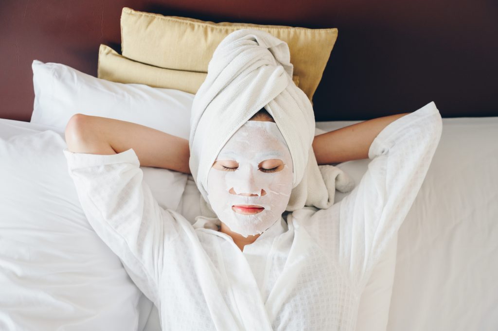 jeune femme en peignoir, allongée avec un masque bie-être