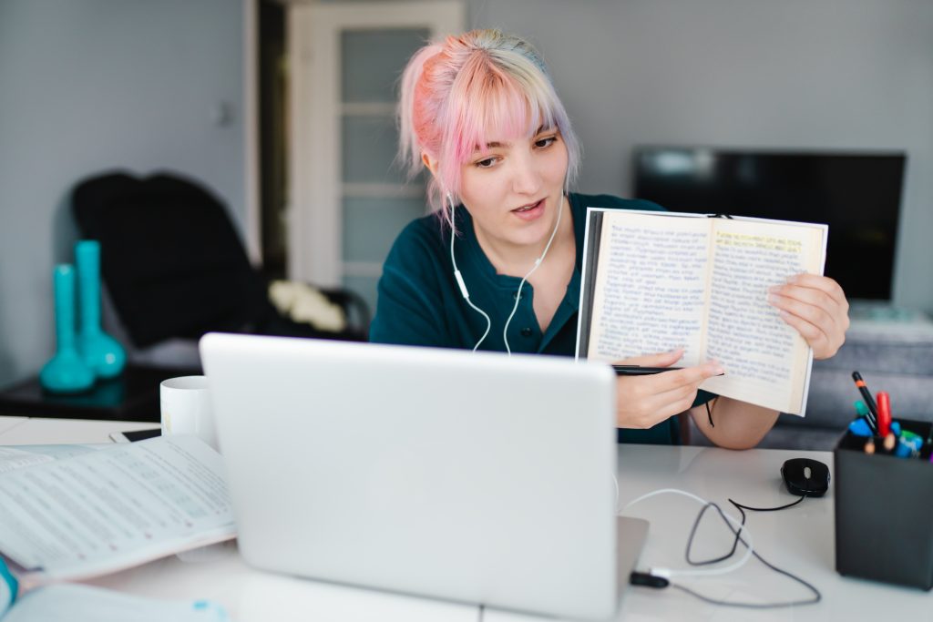 jeune femme montrant un livre à une webcam