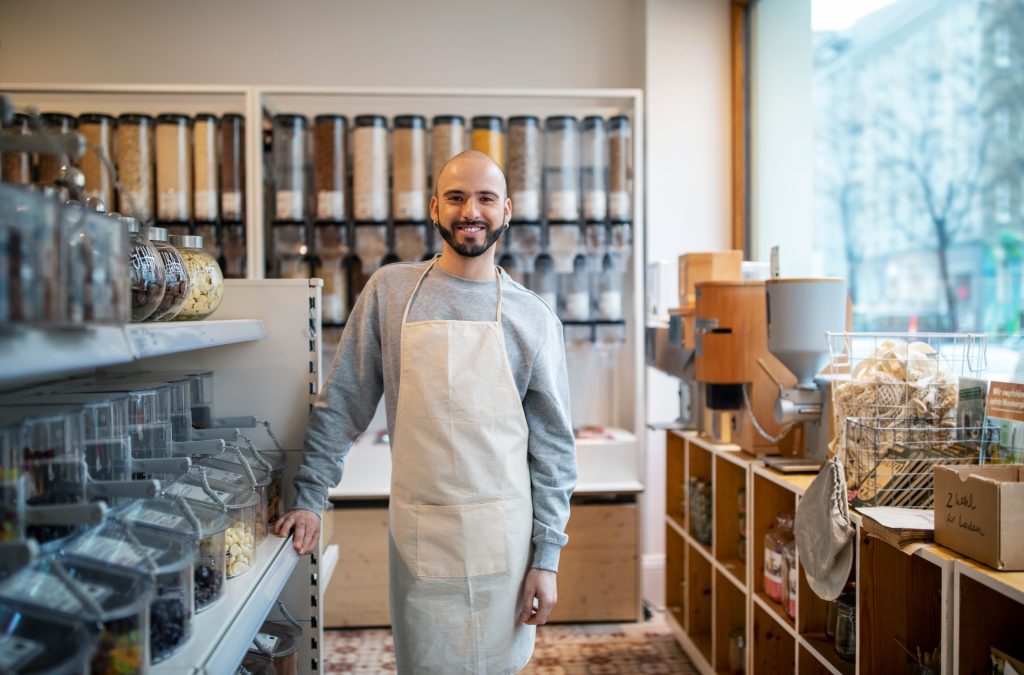 jeune avec un tablier dans une boutique de nourriture en vracs une