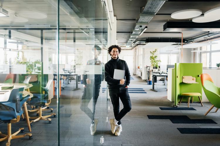 alternant souriant un dossier à la main dans les bureaux de son entreprise de formation