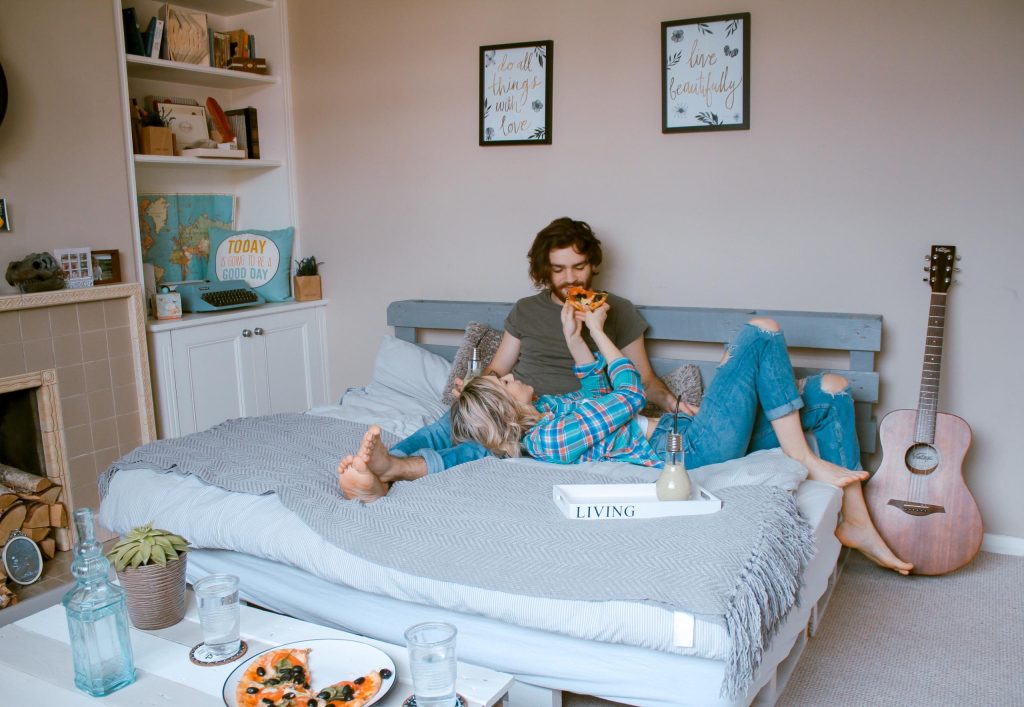 couple mangeant de la pizza dans un lit