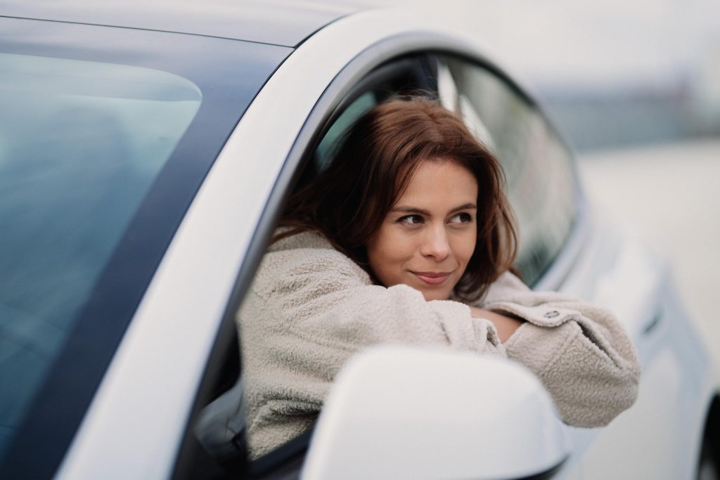 jeune femme sortant la tête par la fenêtre conducteur d'une voiture