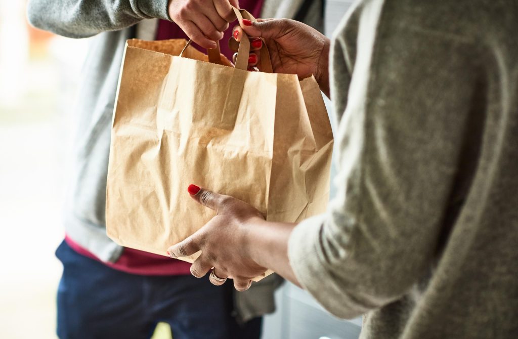 Woman holding paper bag with take out food, home delivery, food order, takeaway