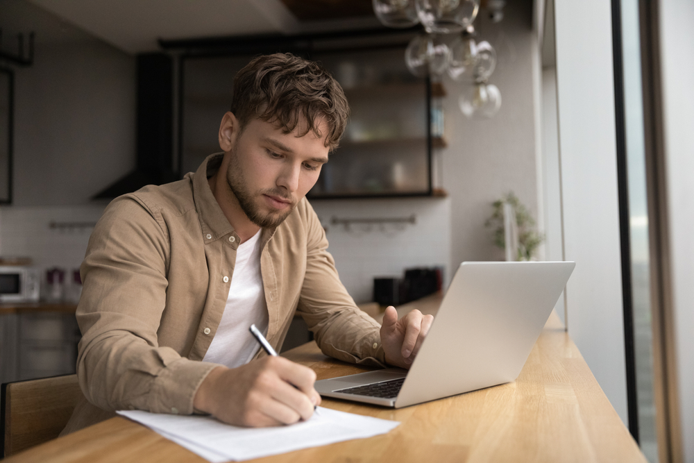 jeune homme prenant des notes sur un carnet