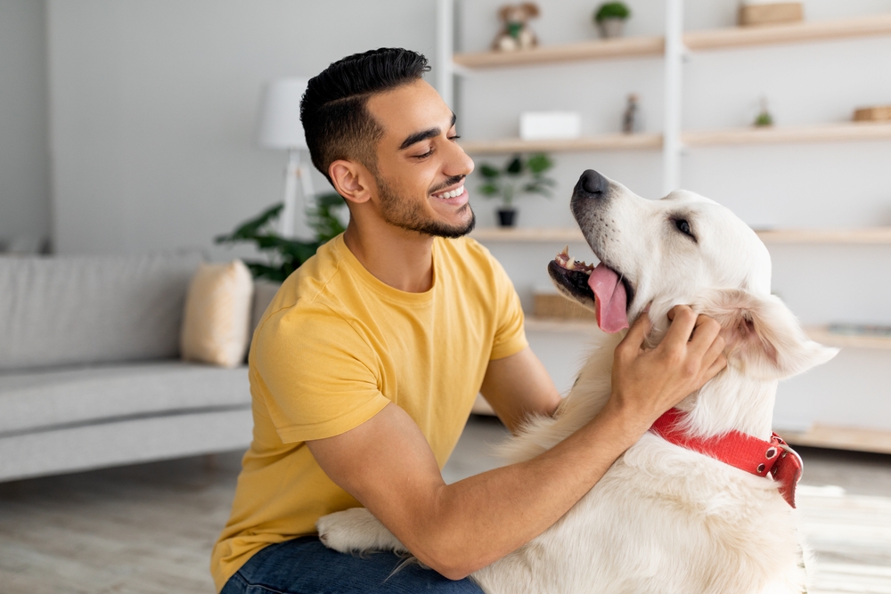 Un joyeux jeune homme oriental qui joue avec son animal de compagnie à la maison