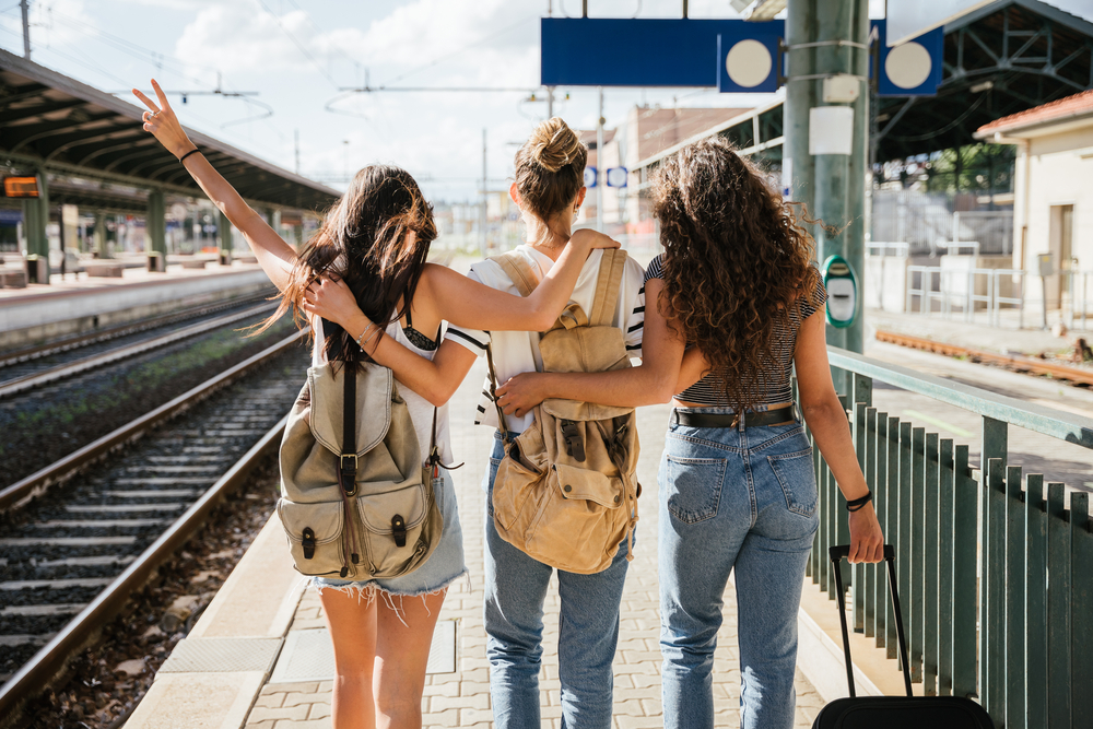 Trois jeunes femmes belles à la gare pour prendre le train pour leurs vacances ensemble